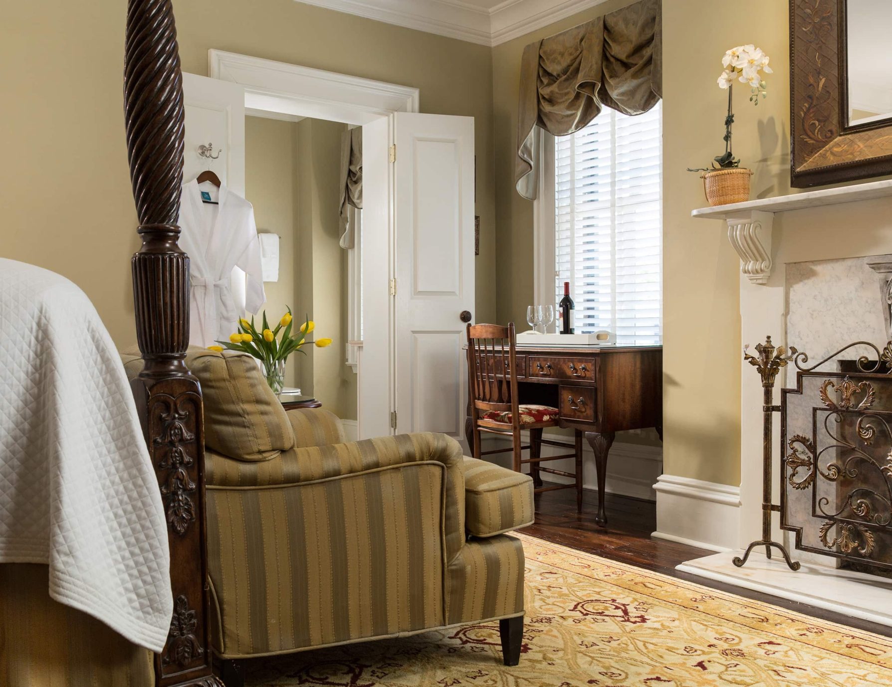 A cozy couch in front of a fireplace with a writing desk near a window